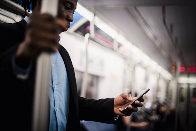 African American man on a subway holding a phone