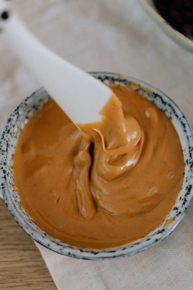 Jar filled with peanut butter with a white knife