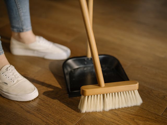 broom sweeping the floor into a dustpan 