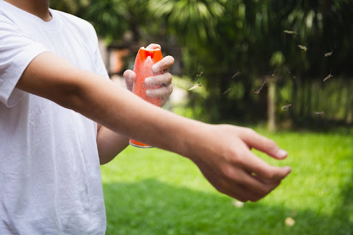 Spraying bug spray on arm